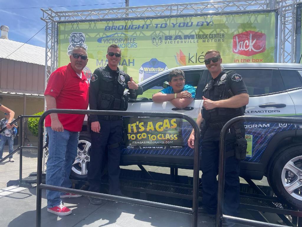 Student sitting in car they won with Oak principal and school police