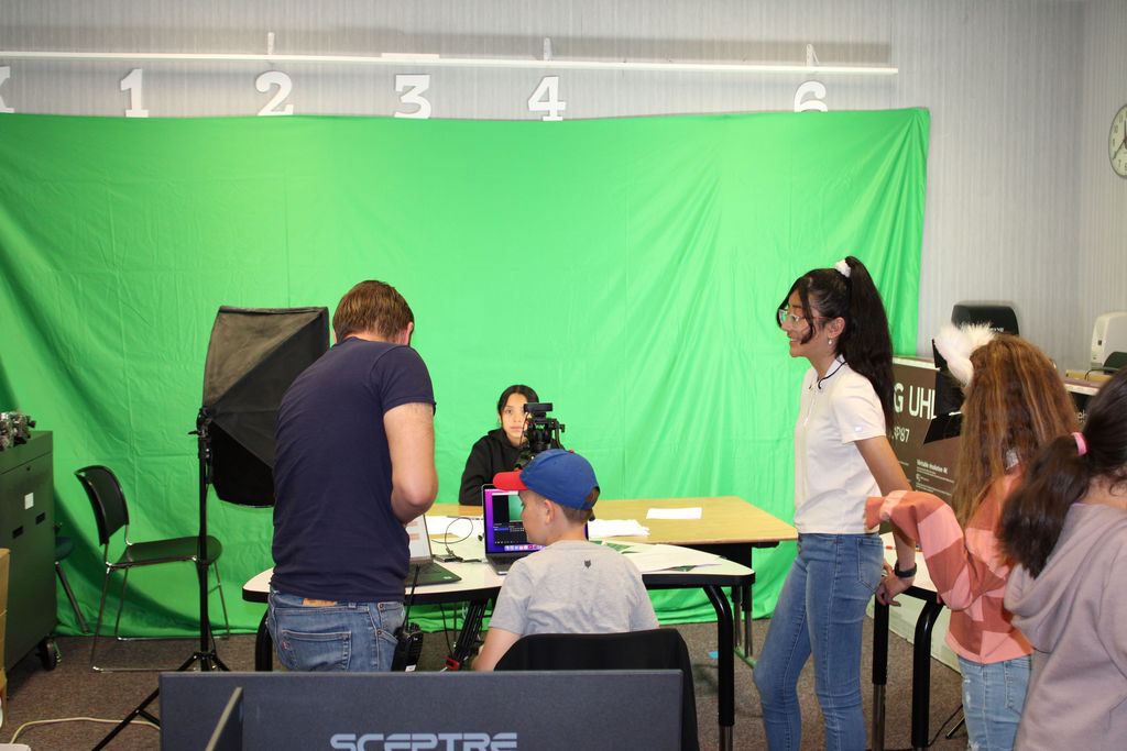 students and mr. stuart in front of green screen