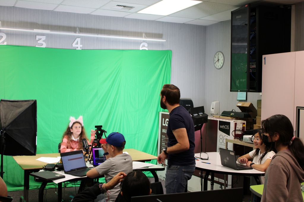 students and mr. stuart in front of green screen