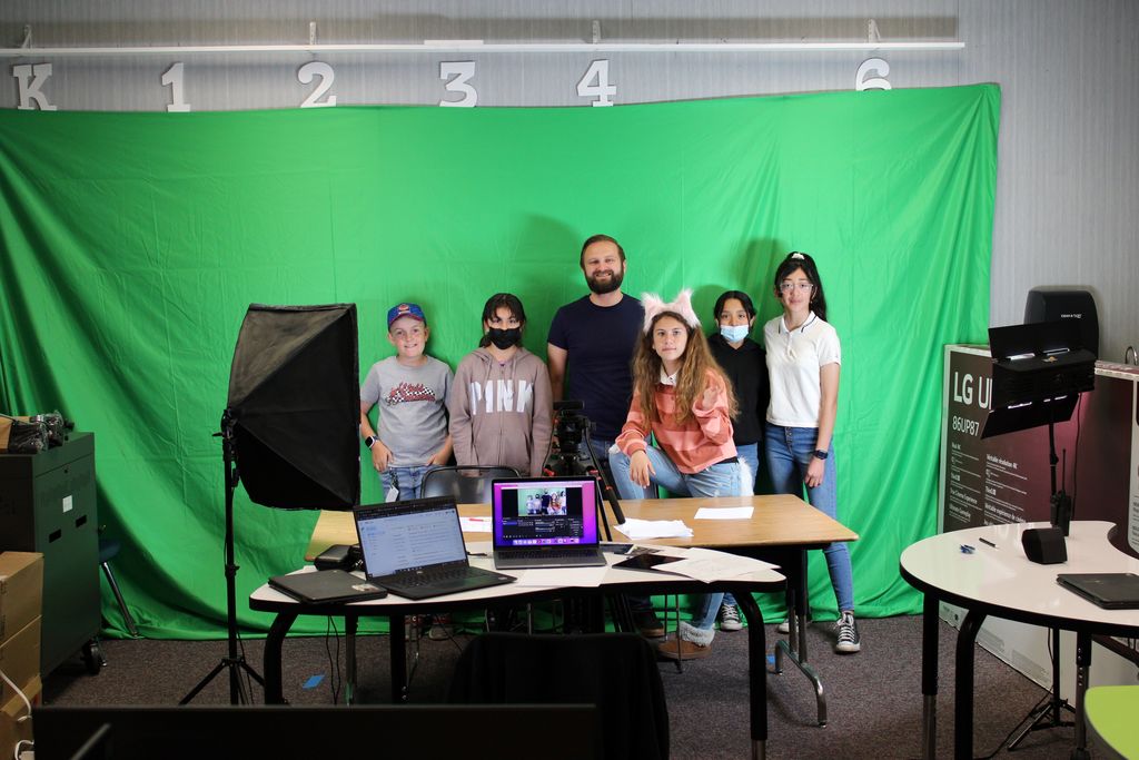 students and mr. stuart in front of green screen